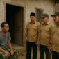 Seorang warga duduk di depan rumahnya saat didatangi tiga orang yang mengenakan seragam mirip perangkat desa. Gambar ini hanya ilustrasi dan bukan dokumentasi kejadian sebenarnya.
