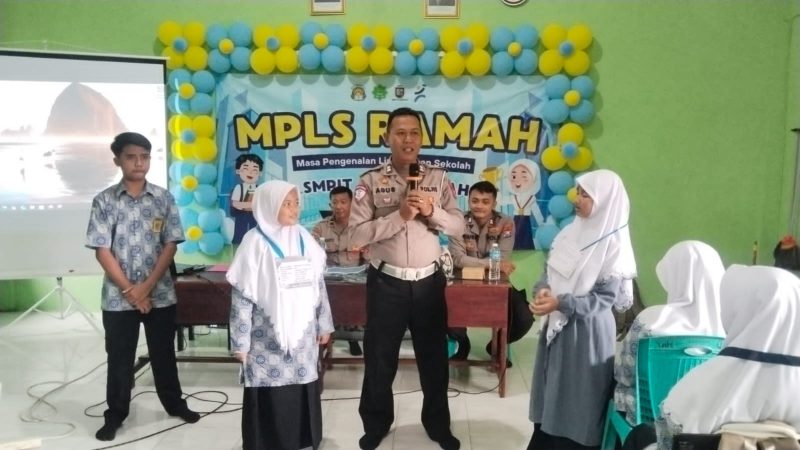 Foto: Aiptu Agus Mariono dari Satlantas Polres Sumenep berinteraksi dengan dua siswi SMPIT Al-Hidayah yang maju ke depan saat sesi edukasi tertib lalu lintas dalam rangka Operasi Patuh Semeru 2025.  