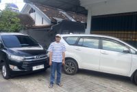 Foto: Koordinator AMSP Nurahmat berdiri di depan dua mobil yang digunakan penyidik Kejati Jatim saat penggeledahan rumah Korkab BSPS Sumenep, Selasa (8/7/2025).