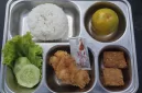 Foto: Menu Program Makan Bergizi Gratis (MBG) berisi nasi, ayam goreng, tempe, sayur, buah, dan sambal dalam wadah saji.  