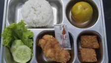 Foto: Menu Program Makan Bergizi Gratis (MBG) berisi nasi, ayam goreng, tempe, sayur, buah, dan sambal dalam wadah saji.  