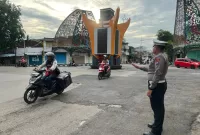 Foto: Bripka Taufik Rahman, petugas Satlantas Polres Sumenep, saat mengatur arus lalu lintas di Simpang Empat Jalan Halim Perdana Kusuma, Kota Sumenep, Selasa (11/11/2025).