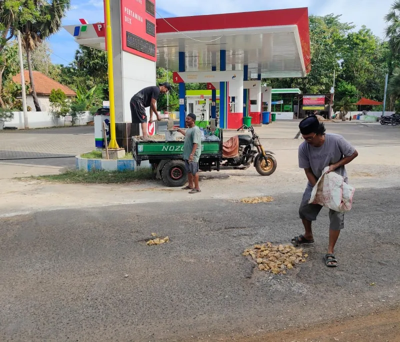 Foto: Warga menambal jalan berlubang secara swadaya di Jalan Raya Dungkek; tampak Bapak Galib (kopyah hitam, berkacamata) ikut turun langsung memperbaiki jalan.