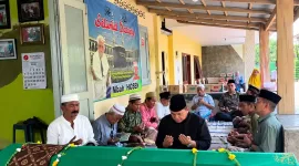 Foto: Ahsanul Qosasi, berkemeja hitam dan berpeci hitam, saat mendoakan Mbah Hosen di rumah duka.